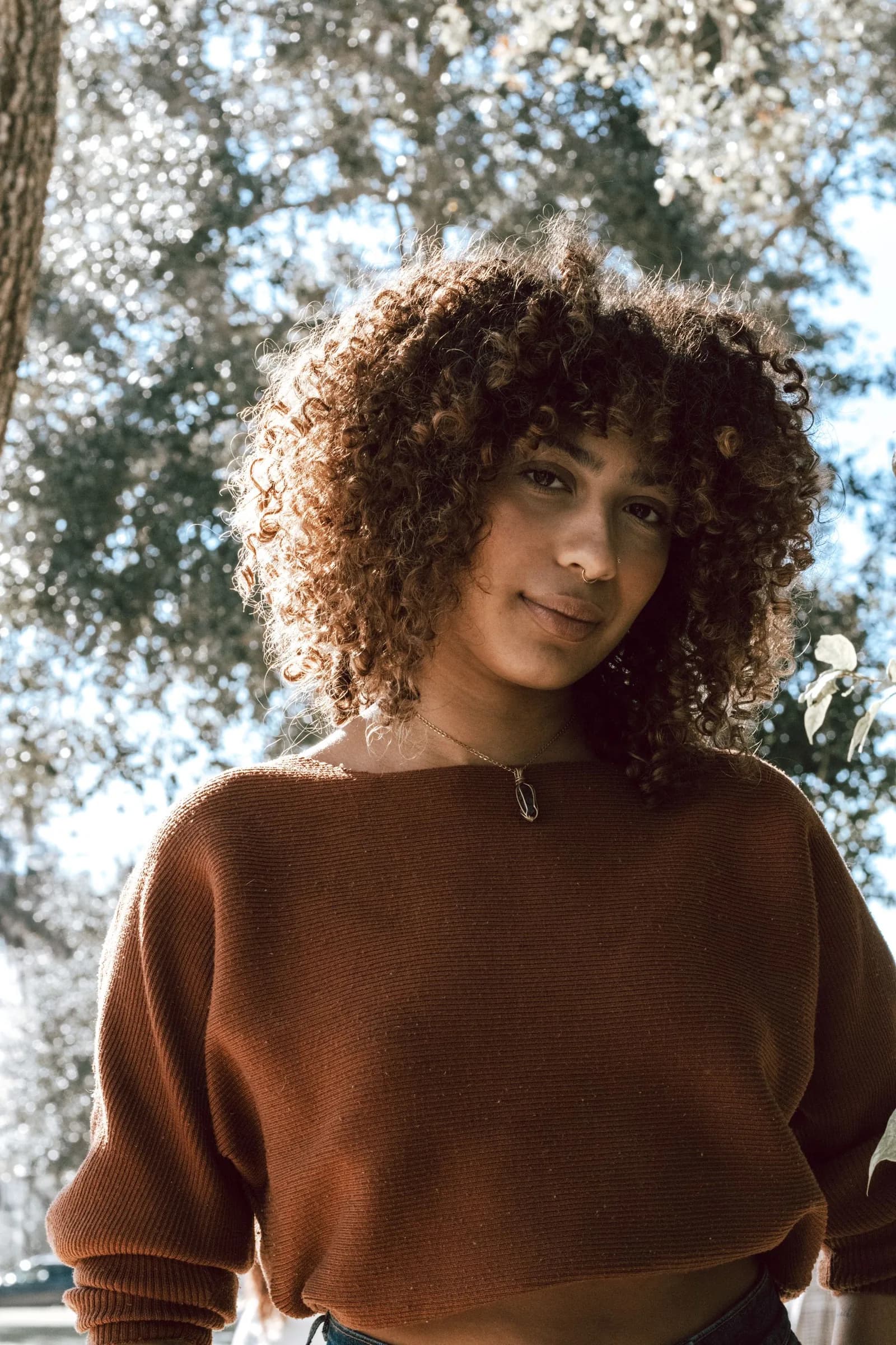 A person with curly hair, backlit by the sun