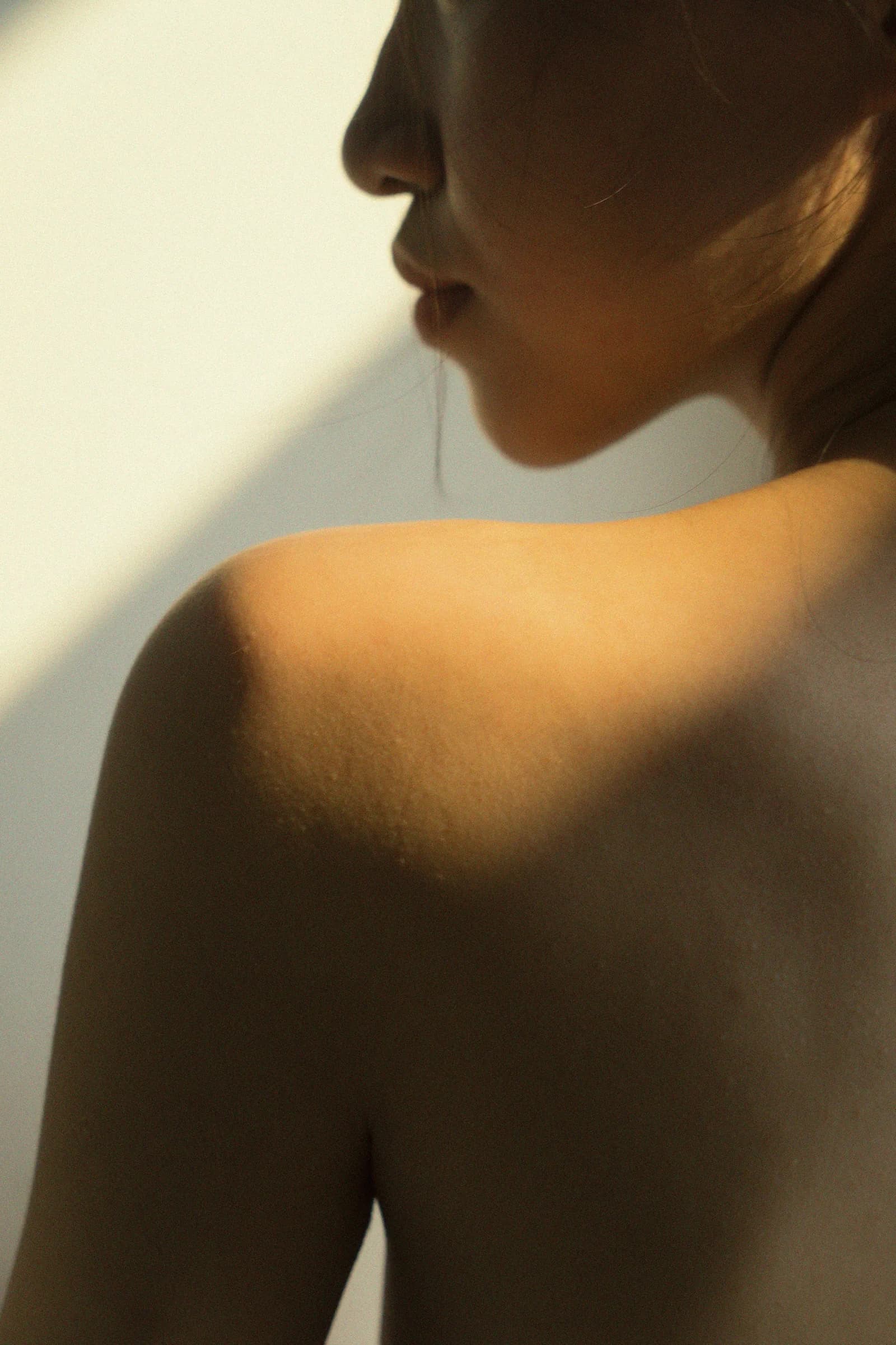 A bare shoulder and neck in soft warm light