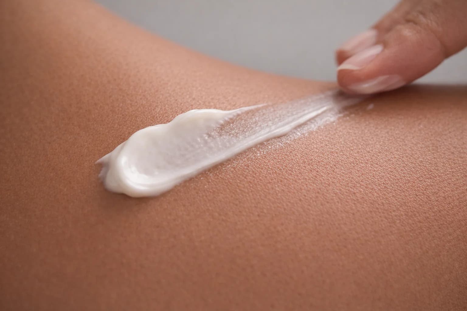 A stripe of white cream drawn across skin with a fingertip.