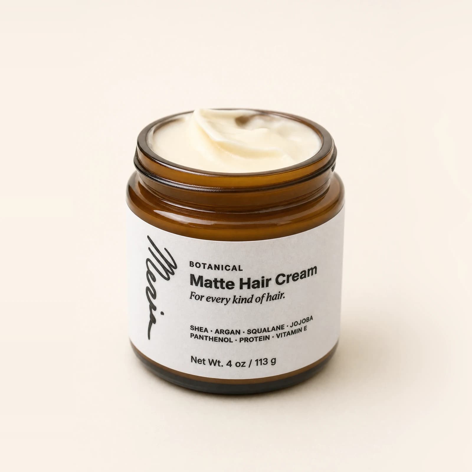 An open jar of Meria Botanical Matte Hair Cream seen from above, the cream visible, on a plain studio backdrop